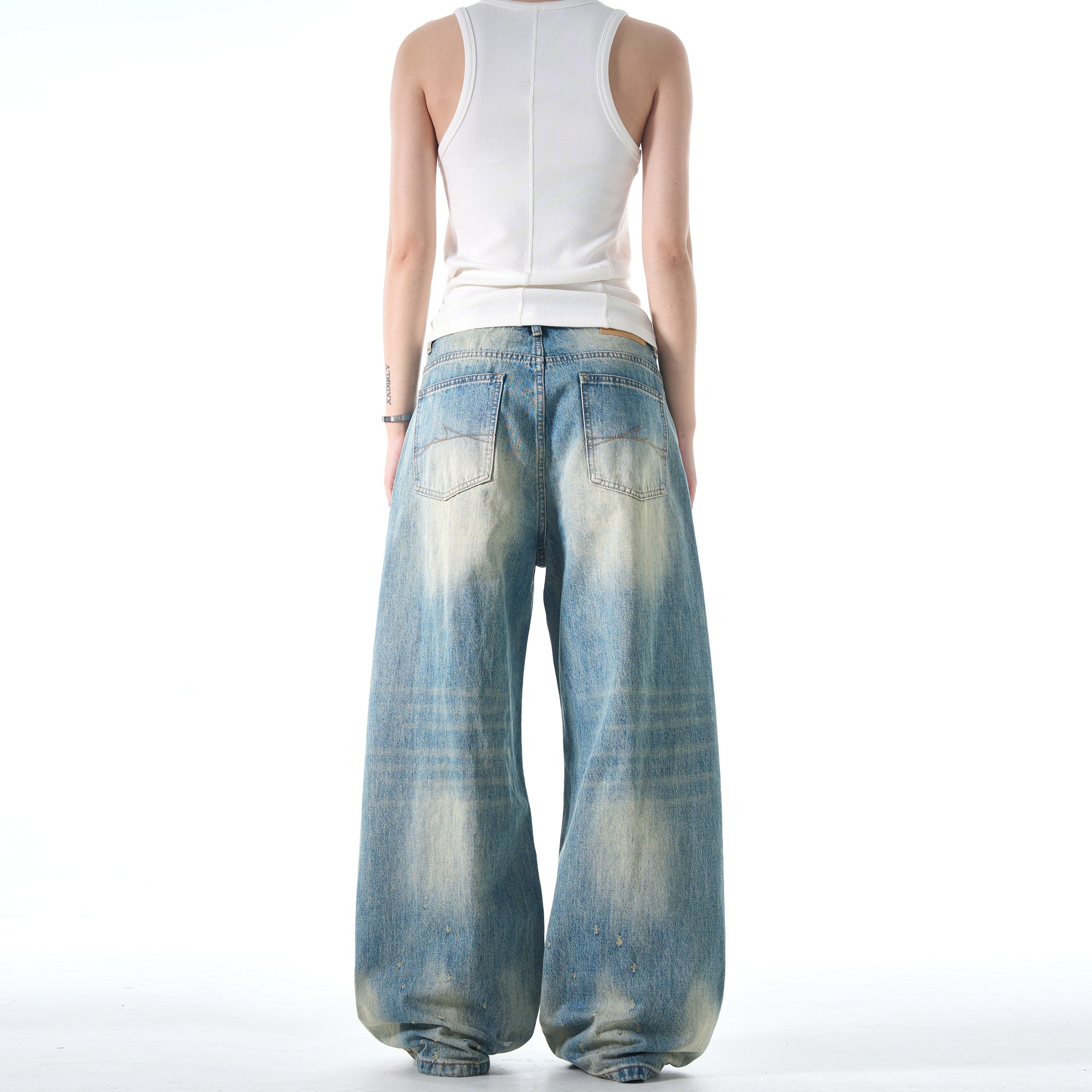 A person wearing a white tank top is shown from behind, modeling a pair of baggy Retro Washed Jeans.