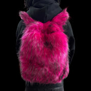 A fluffy hot pink and black Plush Backpacks - Lost Series with bunny ears is worn on a person's back, set against a dark background.