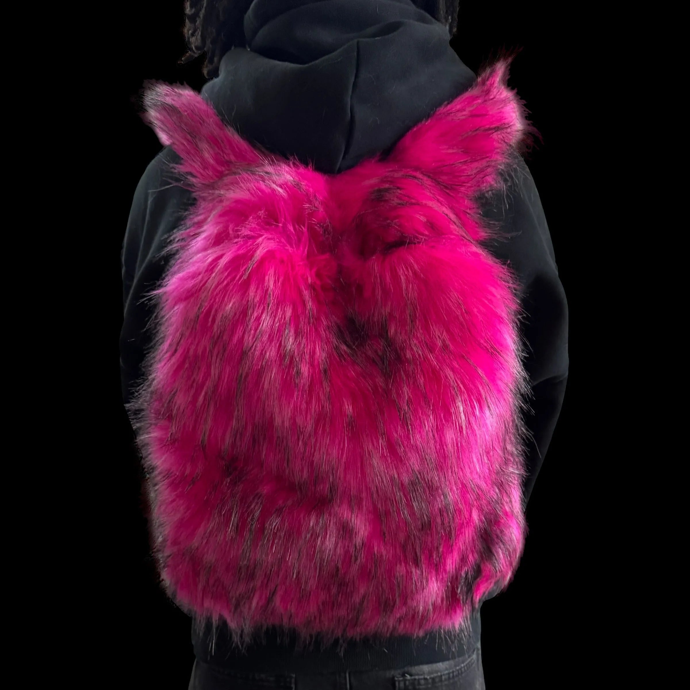 A fluffy hot pink and black Plush Backpacks - Lost Series with bunny ears is worn on a person's back, set against a dark background.
