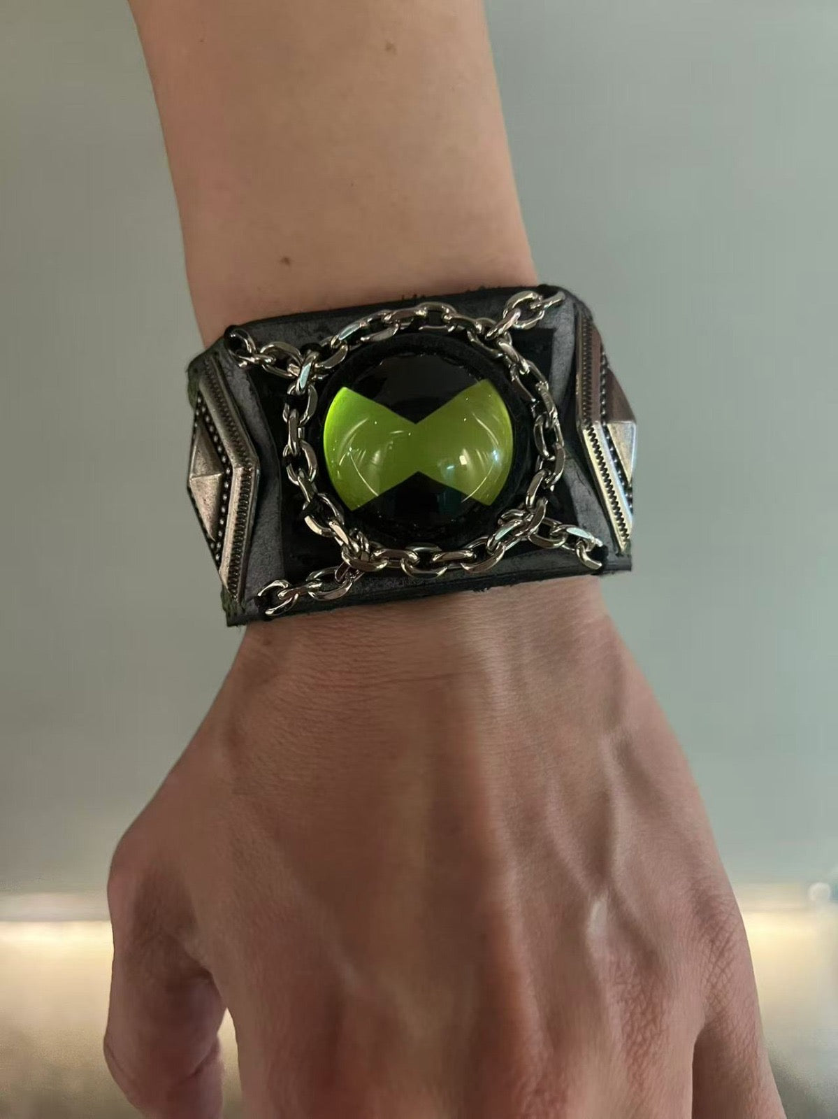 green omnitrix bracelet in a vertical angle wear by a man.