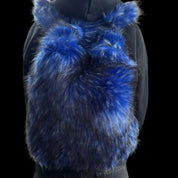 A person wears a fluffy blue and black Plush Backpacks - Lost Series with bunny ears on their back, set against a dark background.
