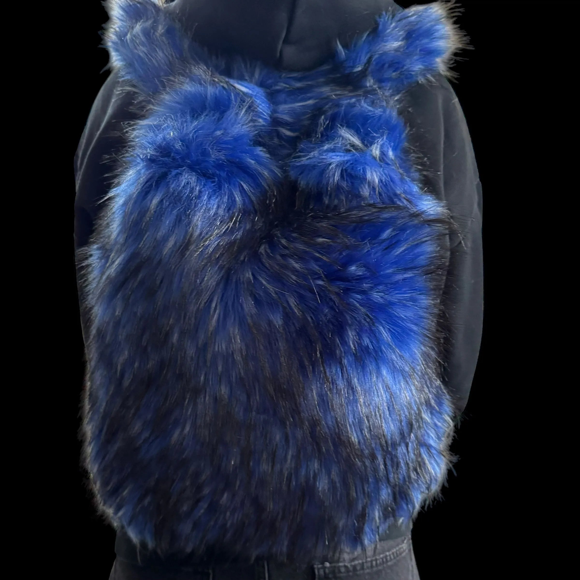 A person wears a fluffy blue and black Plush Backpacks - Lost Series with bunny ears on their back, set against a dark background.