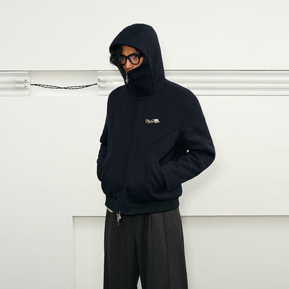 A man wearing glasses models a Herringbone Hooded Jacket in a dark blue, textured fabric. 
