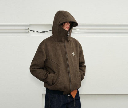 A man wearing a Herringbone Hooded Jacket in a brown, textured fabric. The jacket has a high-zippered collar and a hood that is pulled up.