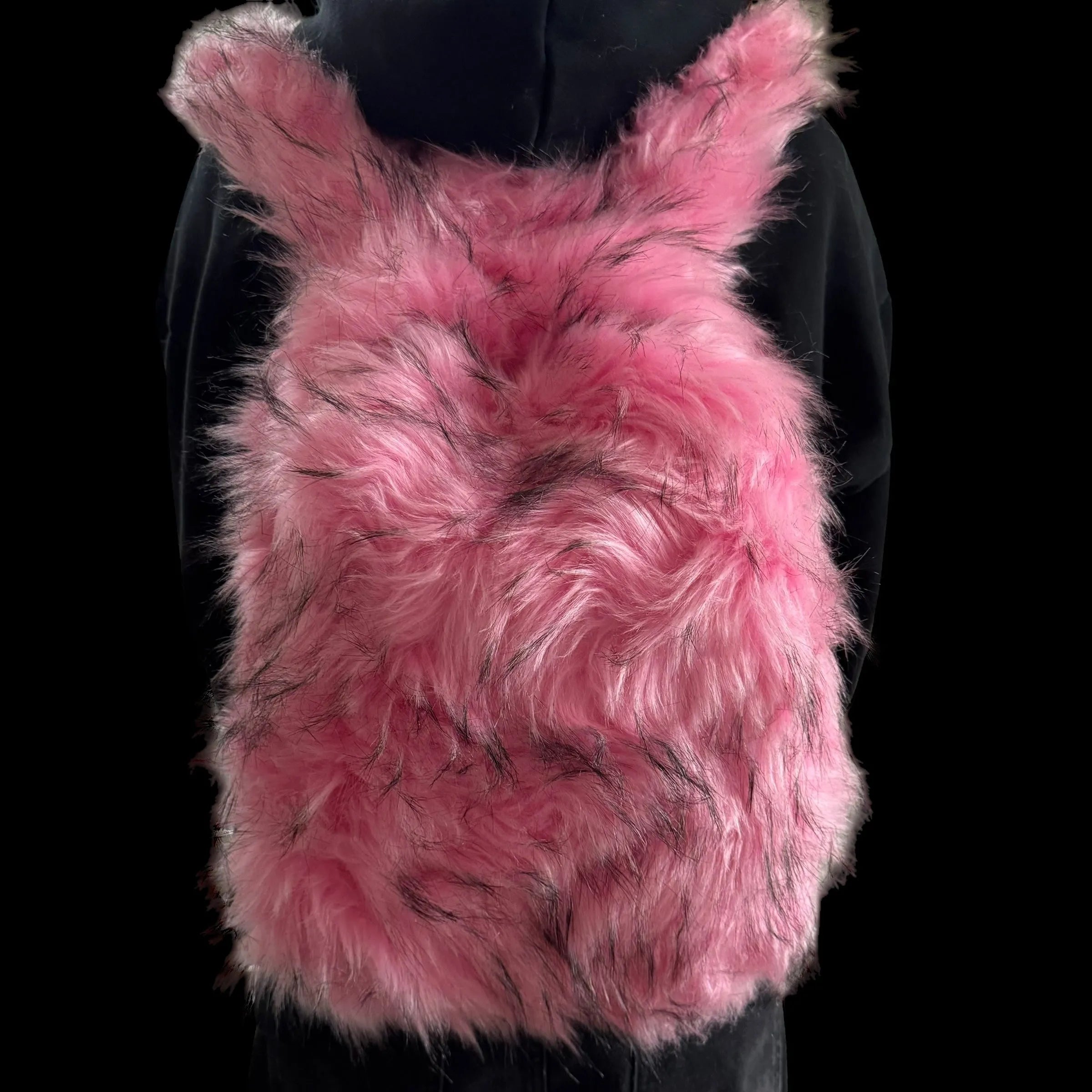 A plush pink bunny backpack with long, pointed ears and dark tufts of fur, from the Plush Backpacks - Lost Series, is worn by a person in a black hoodie.