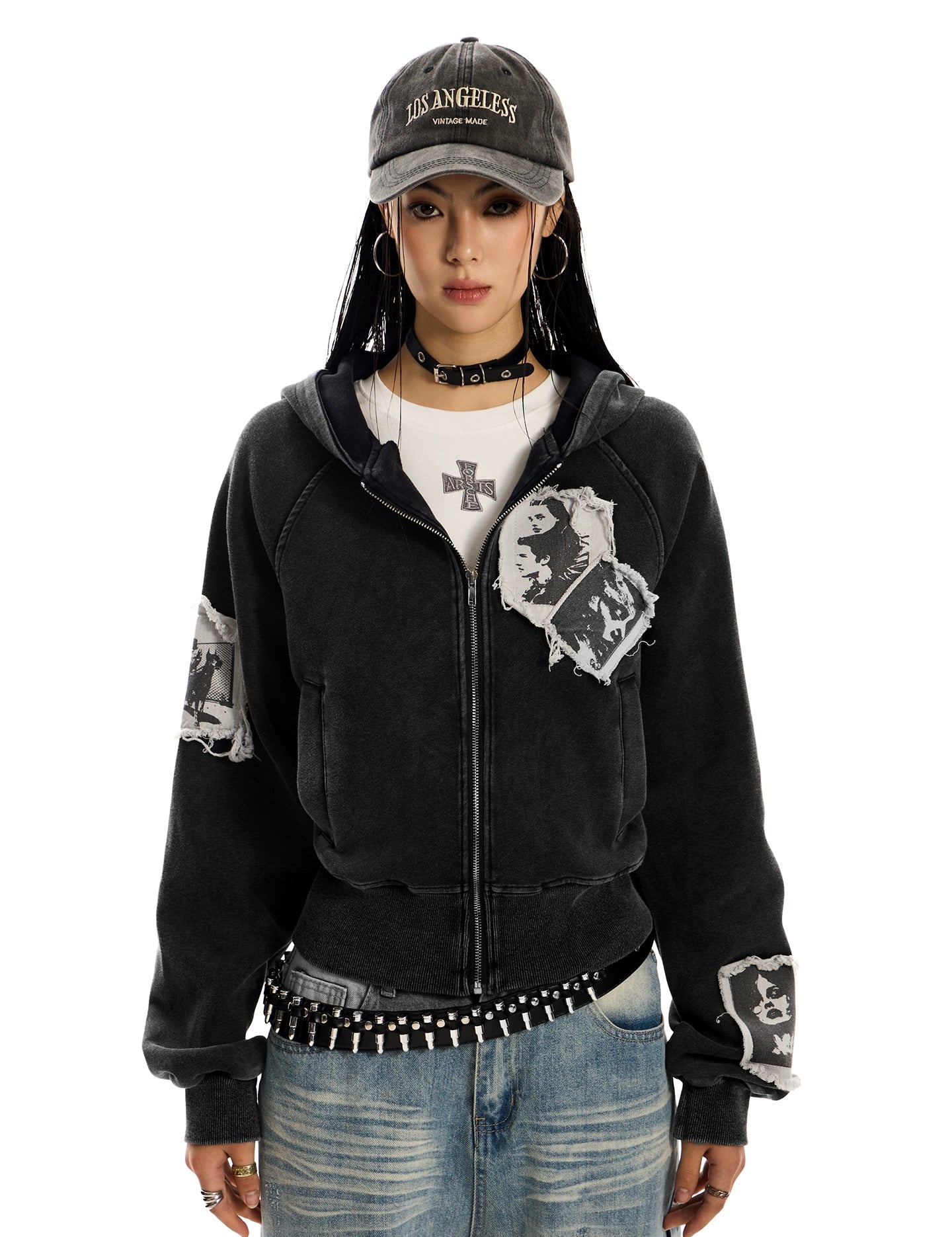 A woman wearing a distressed, black, pocketless "Punk RockStar" hoodie, light wash jeans, and a studded belt.