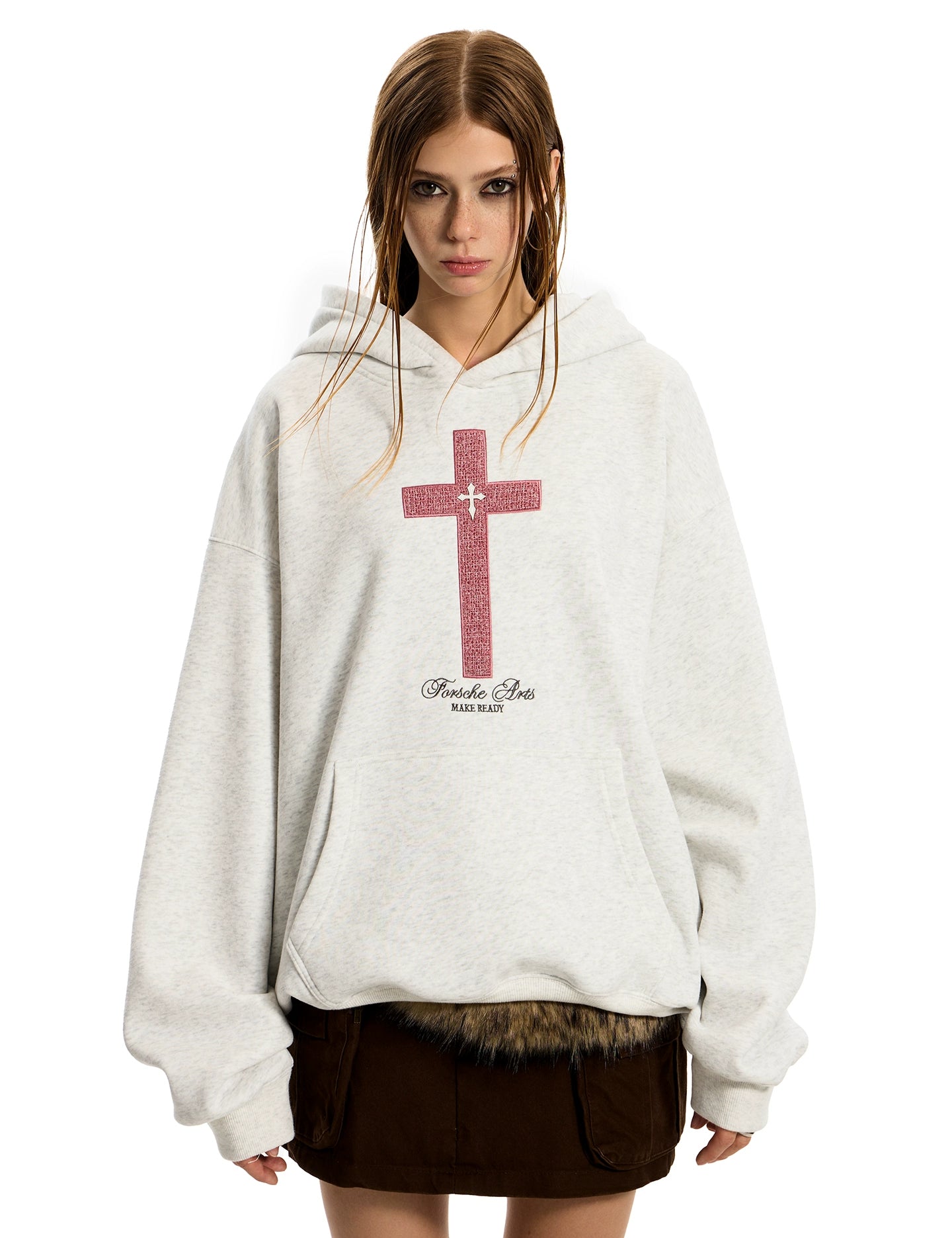 A woman with braided hair wears an oversized light grey GOTHIC HOODIE WOMEN featuring a distressed red cross design over a dark mini skirt.