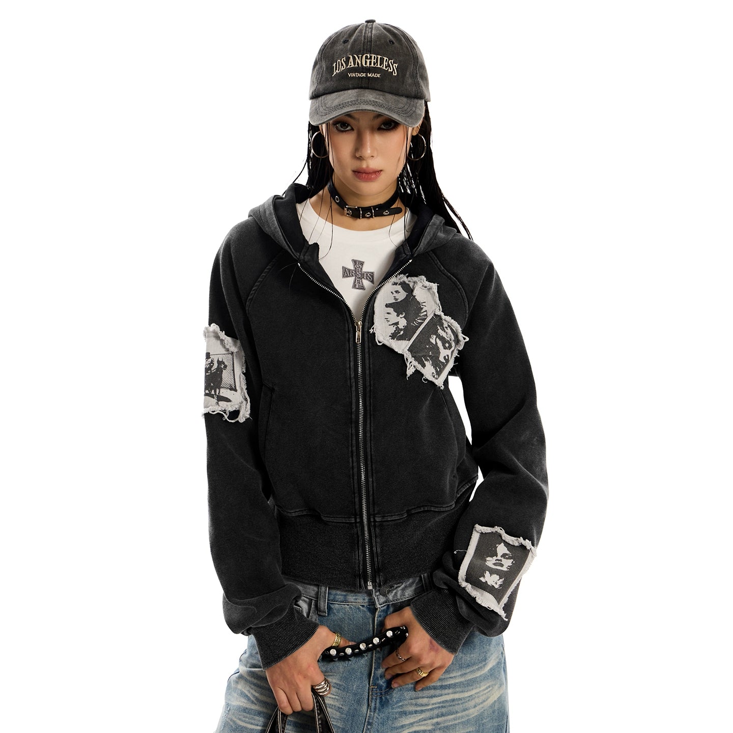 A woman standing, wearing a distressed black pocketless hoodie .