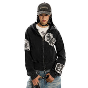 A woman standing, wearing a distressed black pocketless hoodie .