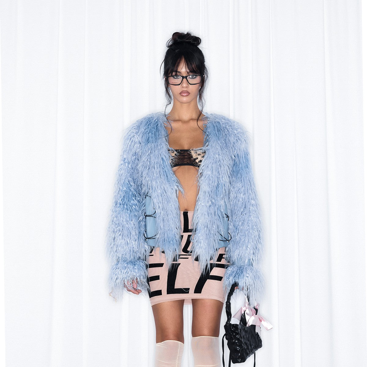 A woman wearing light blue "Women's Blue Fur Coat - NOLA*blue" holding a small black bag.