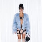 A woman wearing light blue "Women's Blue Fur Coat - NOLA*blue" holding a small black bag.