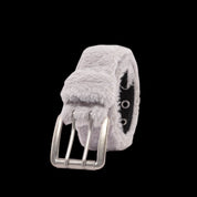 A closeup shot of a grey fur coat with belt that has a silver buckle and two rows of eyelets, set against a black background.