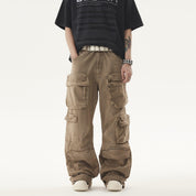 A person stands wearing a black t-shirt and light brown Heavy duty Vibe Cargo Jeans with multiple large pockets, accessorized with a studded white belt and bracelet.