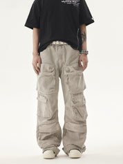A person wears a black t-shirt and light-colored Heavy duty Vibe Cargo Jeans with numerous large cargo pockets, paired with a studded white belt and white sneakers.
