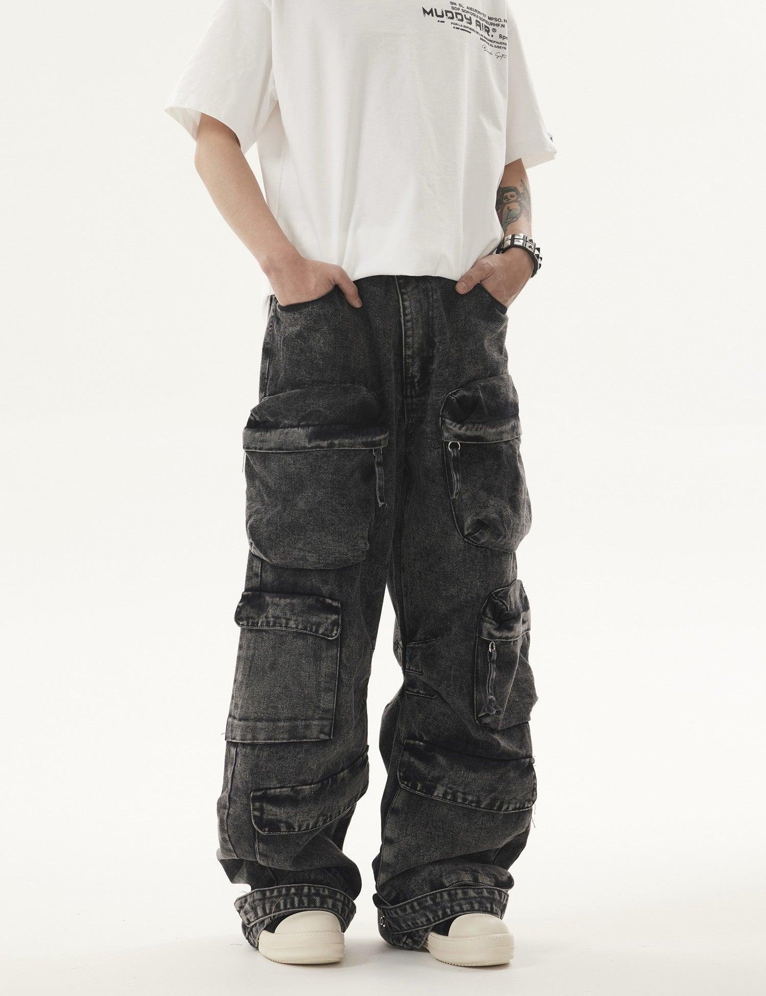 A person stands with hands in the pockets of dark, acid-wash Heavy duty Vibe Cargo Jeans featuring multiple cargo pockets, paired with a white t-shirt and white sneakers.