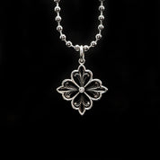 A delicate, silver filigree melody necklace featuring a floret design with a sparkling diamond in the center, presented on a black background.