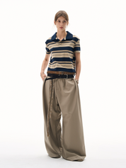 A full-length shot of a woman wearing a polo shirt retro with navy and tan stripes and a navy collar. 
