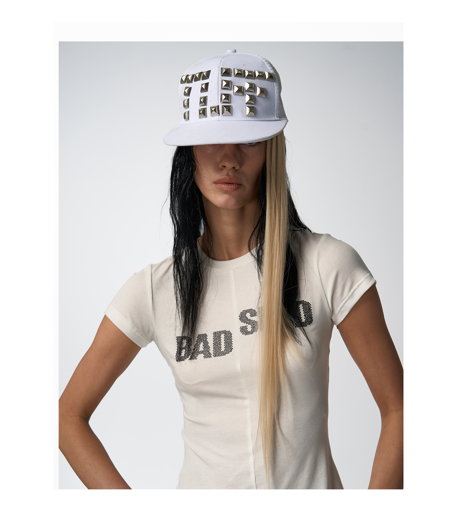 A woman with white t-shirt with "BAD SISTER" written in black sparkly letters, embodying the "rebel t shirts women" style.