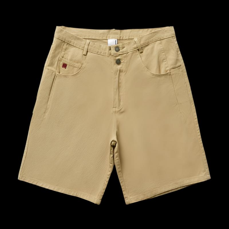 A khaki-colored pair of Remedy Straight Workwear Mid-Length Jorts is shown on a mannequin, while another image shows a person modeling the black version of the shorts, paired with a gray T-shirt and sneakers.