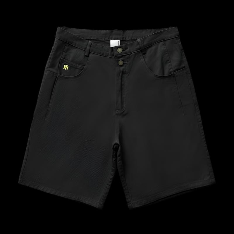 A black pair of Remedy Straight Workwear Mid-Length Jorts is displayed flat against a dark background, featuring subtle yellow stitching on the coin pocket, a button fly, and two large front pockets.