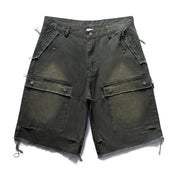 A pair of dark, distressed Remedy Washed Tassel Workwear Jorts with large cargo pockets and a frayed hem is displayed against a white background.