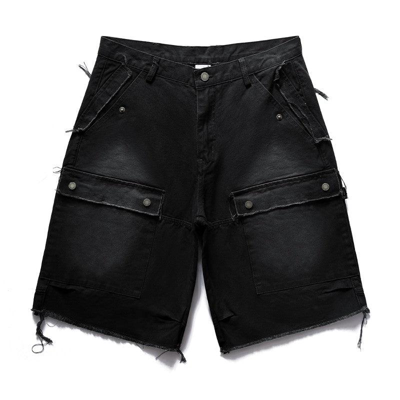 Two pairs of distressed Remedy Washed Tassel Workwear Jorts—one black and one dark gray—are displayed, both featuring large front cargo pockets with metal snaps and frayed, tasseled hems.
